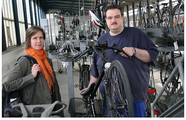Uni-Dozentin Ariane Cordes aus Schwerte lässt ihr Fahrrad regelmäßig in der Station. Mitarbeiter Ingo Bade schiebt es in einen Ständer. - © FOTO: HOLGER KOSBAB