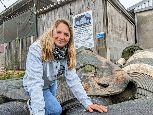 Vorsitzende Melanie Schneider sitzt auf einem Haufen von Kunstrasenrollen für den Auslaufplatz ihrer kranken Pferde. - © Burkhard Battran