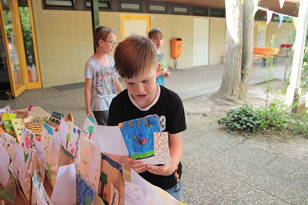 Selbst gestaltet: Shawn (8) schaut sich eine der Tüten mit dem Saatgut an, die seine Mitschüler bemalt haben. - © NW