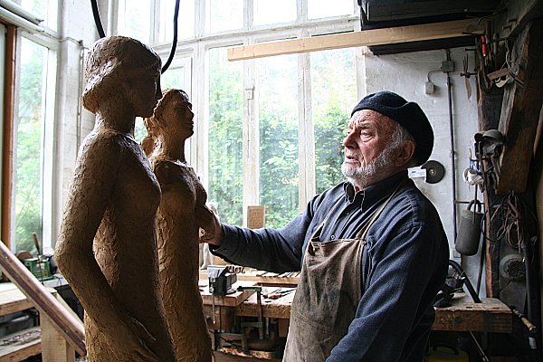 Bruno Buschmann mit der typischen Kopfbedeckung in seinem Atelier. Hier arbeitet er an zwei Frauen-Skulpturen. - © Werner Nowak