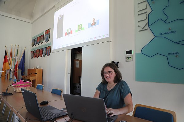 Elena Wiegers, IT-Expertin vom Kreis Höxter, am Laptop vor den Ergebnisbalken in der Aula des Kreishaues. - © Simone Flörke