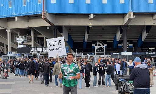 Thomas Melchior hält am vergangenen Freitag sein "Wette verloren"-Schild vor der Bielefelder Schcüo-Arena in die Höhe. Dahinter reihen sich die Arminia-Fans in die Schlange ein, um rechtzeitig zum Spiel gegen den 1. FC Magdeburg ins Stadion zu kommen. - privat