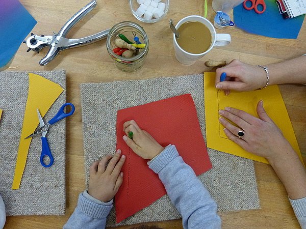 Zwei große Rauten, in der Größe von etwa 45 mal 25 Zentimeter, werden auf das Wellpapier gezeichnet und ausgeschnitten. Nun wird auf beiden Seiten ein Rand von circa fünf Zentimetern aufgemalt und mit der Prickelnadel ausgestochen.