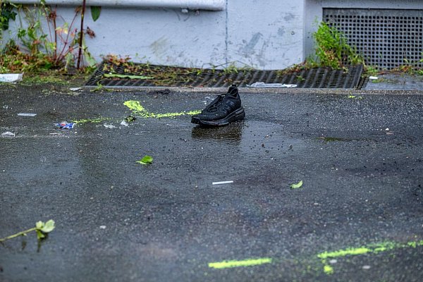 Ein Schuh steht auf einem Gehweg in der Nähe des mutmaßlichen Tatorts in Passau. Polizeimarkierungen sind zu sehen. - © Armin Weigel/dpa