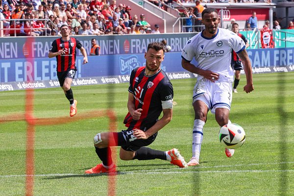Lukas Froede vom FC Ingolstadt 04 (l.) kommt hier schon zu spät gegen den Arminen Noah Joel Sarenren Bazee. - © IMAGO/Eibner