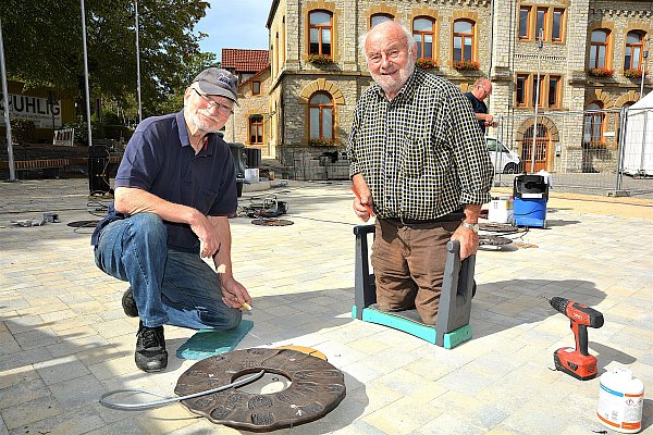 Bruno Buschmann bekommt beim Anbringen der Bronzeplatten für die Wasserspiele auf dem Rathausplatz im Jahr 2019 Hilfe von Werner Nowak (l.). - © Karin Prignitz