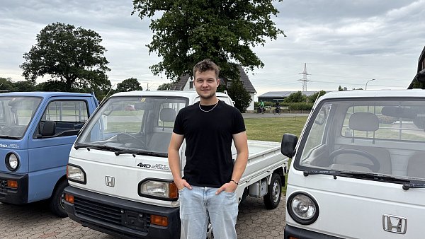 Dominic Brinkmann vor seinen Kei-Trucks. Auf dem Foto gut erkennbar: Die Unterschiede zwischen den in Deutschland zugelassenen eckigen Scheinwerfern und dem runden Original aus Japan. - © Zoé Zacharias