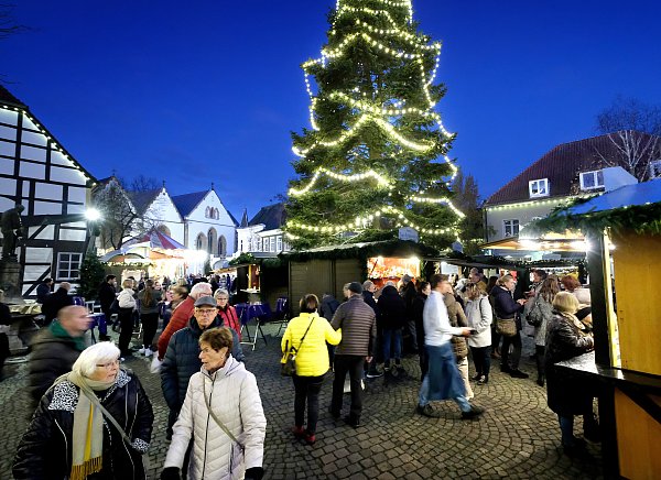 Besucher genießen die festliche Atmosphäre auf dem Christkindlmarkt in Rheda-Wiedenbrück unter dem strahlenden Weihnachtsbaum. - © Andreas Frücht