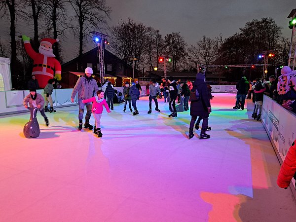 Familien genießen eine fröhliche Schlittschuhpartie bei "Wiedenbrück on Ice", umgeben von bunten Lichtern und festlicher Stimmung. - © Marion Pokorra