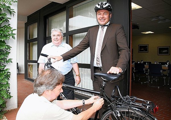 Polizist Hans-Joachim Dubbel bringt das neue Kennzeichen am Rad von Landrat Ralf Niermann an, links Mindens stellv. Bürgermeister Egon Stellbrink. - © FOTO: STEFAN KOCH