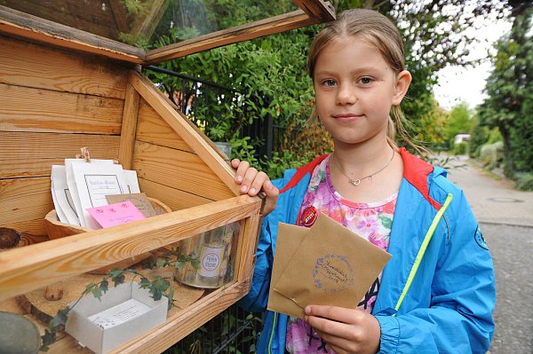 Kreativ: Merle Scholz (8) zeigt den Kasten am Gartenzaun der Familie, aus dem sich Nachbarn und Passanten Tüten mit Samen mitnehmen können. - © Stefanie Boss