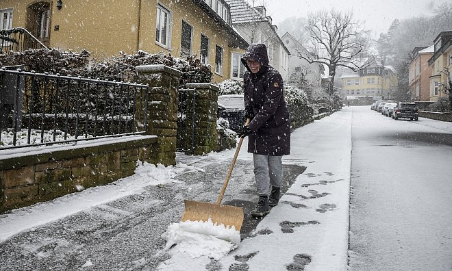 Eine Person räumt den verschneiten Gehweg in einem Wohngebiet, um für sichere Passagen zu sorgen. - Jörg Dieckmann