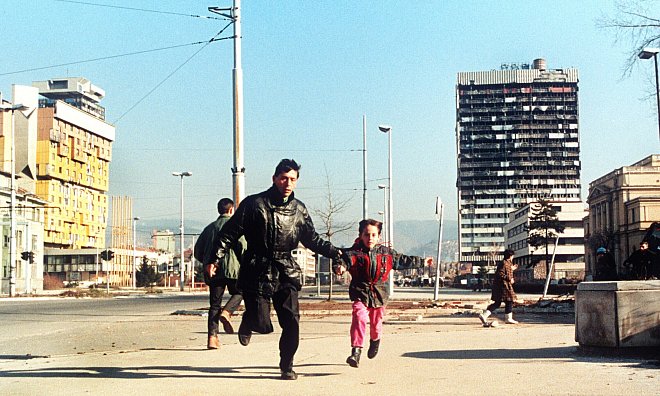 Szene aus dem Jahr 1994: Ein Einwohner Sarajvos rennt mit seinem kleinen Sohn an der Hand über die Straße, um sich in Sicherheit vor Heckenschützen zu bringen. - picture alliance / epa Ch.Simon/epa/dpa
