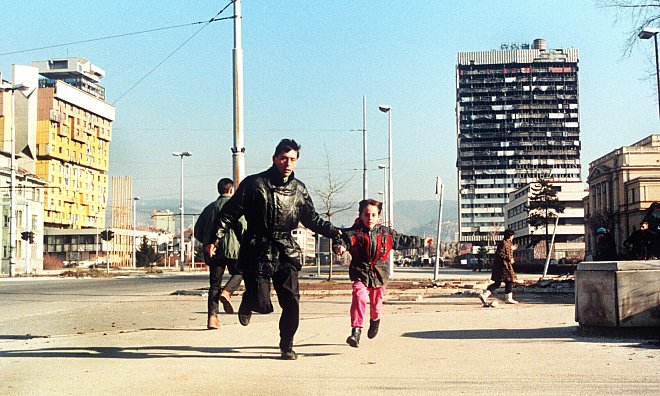 Szene aus dem Jahr 1994: Ein Einwohner Sarajvos rennt mit seinem kleinen Sohn an der Hand über die Straße, um sich in Sicherheit vor Heckenschützen zu bringen. - picture alliance / epa Ch.Simon/epa/dpa