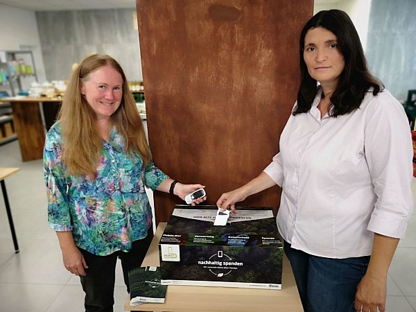 Alexandra Feege und Nicole Robrecht (v.l.) spenden ihr altes Handy in die Mobile-Sammelbox, nachdem es über 12 Jahre lang im Schrank verstaubte. - © Nathalie Voigt