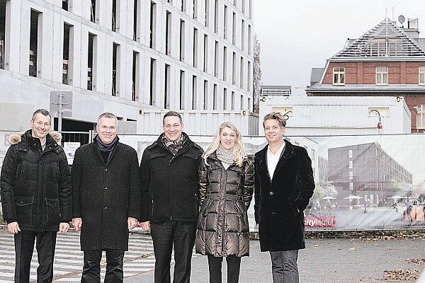 Im Zeitplan: Marco Lorenz (Leiter Finanzen und Prokurist der Tappe Holding, v. l.), Tobias Voss (Geschäftsführer Fidelis Hospitality Gruppe), Björn Hackert, Annette Driesen (beide Intercity-Hotel) und Andreas Oehme (Geschäftsführender Gesellschafter Sternzeit Catering) stehen vor dem Rohbau des Marta-Hotels. - © Peter Steinert