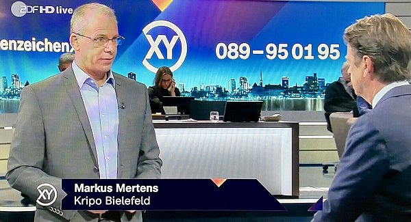 Erster Kriminalhauptkommissar Markus Mertens, Leiter der "Mordkommission Stadion" im Gespräch mit Aktenzeichen-Moderator Rudi Cerne. - © Screenshot: Altenzeichen XY / ZDF