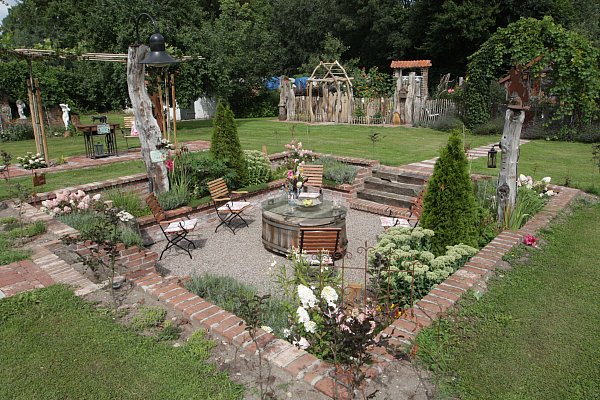Das Schmuckstück im Garten von Gerlinde Kersting ist der sogenannte Senkgarten. Mit Freunden zusammen hob sie ein großes Loch aus, die Wände verkleidete sie mit alten Ziegelsteinen, die Treppen bestehen aus alten Eichenbalken und aus einer gut 200 Jahre alten Holzbadewanne wurde der Tisch. - © Uwe Müller