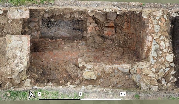 Blick auf die Luftheizung. Teile der Gerölle des Steinspeichers wurden entnommen, die Störung bis auf die Sohle des Feuerungskanals ist durch den Abbruch im 15. Jahrhundert entstanden. - © Orthomosaik: LWL/Peter Hessel