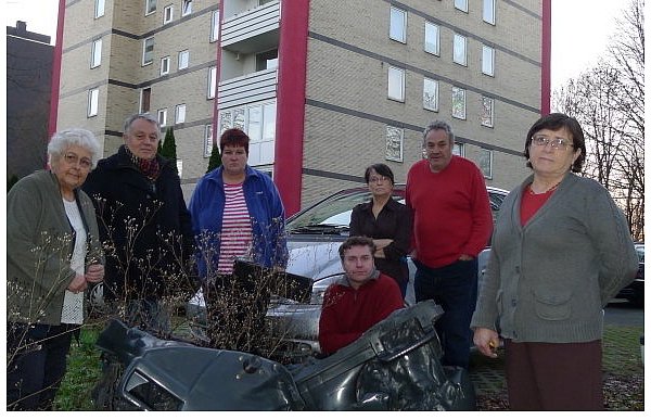 Charlotte Langer (v. l.), Nobert Schulz, Ilona Langer, Risto Urumov, Asta Willert, Wolfgang Rehn und Elvira Geptin vor dem Haus in der Hohoffstraße 14. Vor ihnen liegt der verkokelte Müllbehälter. - © FOTO: HANS-HERMANN IGGES