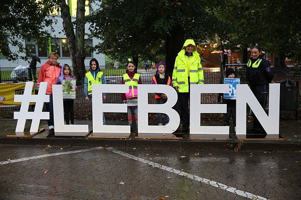 Mit dem Schiftzug "#Leben" machen Polizistinnen, Lehrer und Schüler an der Grundschule Oberbecksen auf die Gefährlichkeit des Verkehrchaos aufmerksam. - © Elke Niedringhaus-Haasper